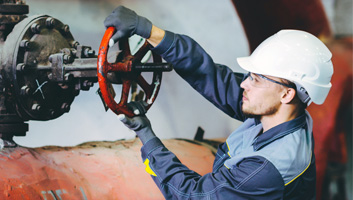 Engineer turning a wheel on a pipe